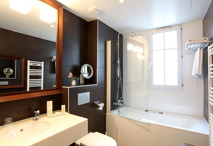 Bathroom at Little Palace Hotel, a gay-popular hotel in Paris' Marais gayborhood. Features a sink, toilet, bathtub, shower, and mirror.