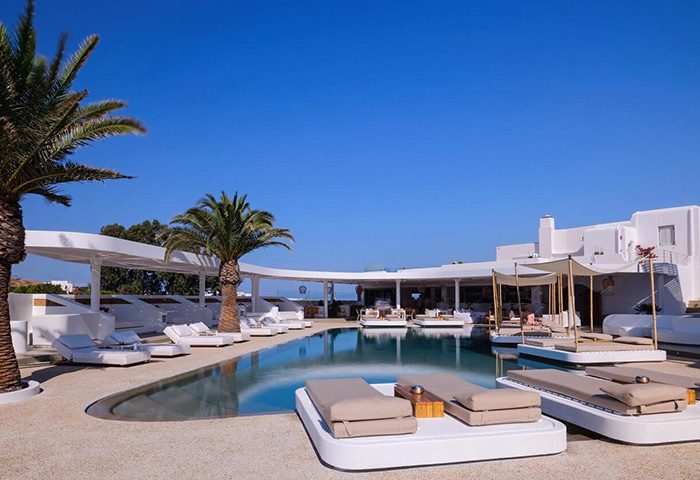 Andronikos Hotel, a gay-popular hotel in Mykonos Town. Poolside loungers and palm trees create a relaxing, luxury atmosphere for gay travelers.