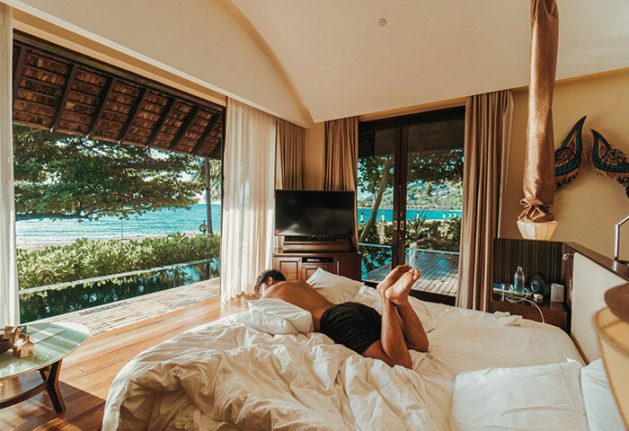 Gay-popular pool villa at Vana Belle, a Luxury Collection Resort in Koh Samui, Thailand. Man relaxing on bed with ocean view.