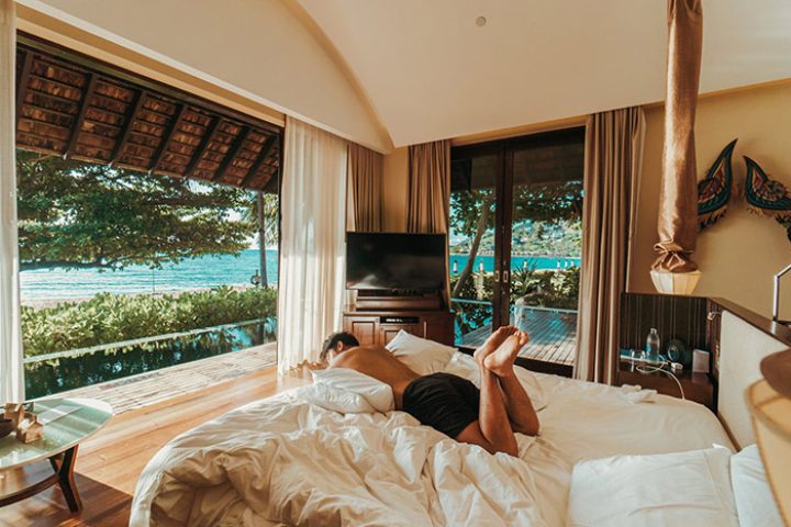 Gay-popular pool villa at Vana Belle, a Luxury Collection Resort in Koh Samui, Thailand. Man relaxing on bed with ocean view.