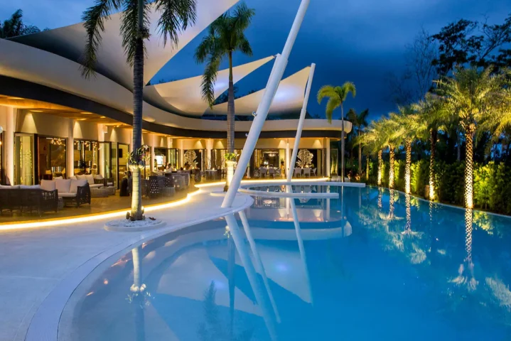The Pavilions Phuket gay resort. Luxury pool at dusk. Upscale dining and lounge areas. Palm trees. Gay travel in Phuket, Thailand.