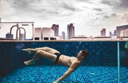 Gay Singapore Hotel Guide: Man swims in the Holiday Inn Express Clarke Quay pool. The hotel offers a rooftop pool with city views.