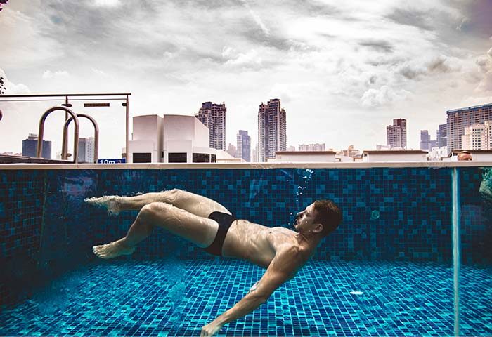 Gay Singapore Hotel Guide: Man swims in the Holiday Inn Express Clarke Quay pool. The hotel offers a rooftop pool with city views.