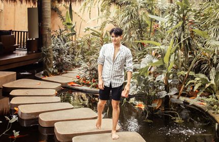 Gay wellness beach resort in Koh Phangan. Man walking barefoot on stepping stones over a pond at Anantara Rasananda Koh Phangan Villas.