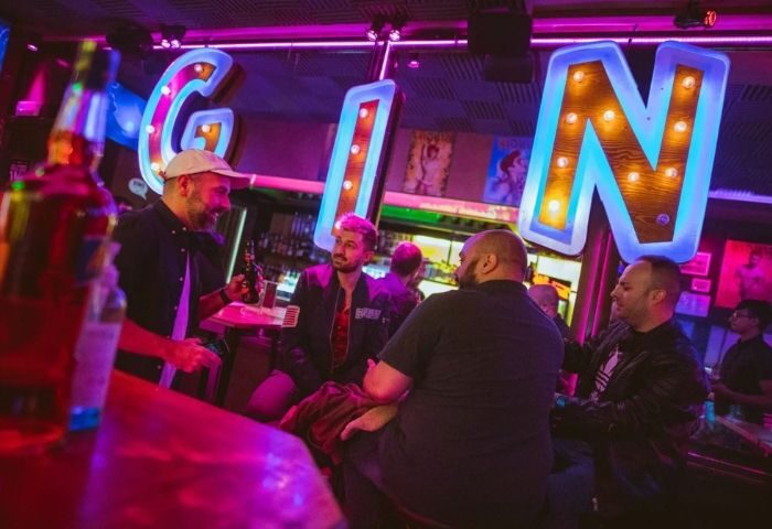 GinGin Gay Bar in Barcelona: Men at the bar with neon GIN sign. A vibrant nightlife spot for gay travelers in Barcelona, Spain.