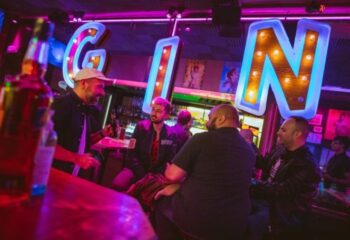 GinGin Gay Bar in Barcelona: Men at the bar with neon GIN sign. A vibrant nightlife spot for gay travelers in Barcelona, Spain.