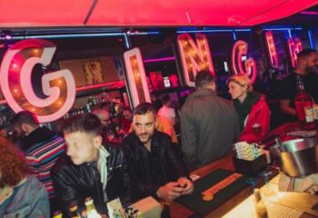 GinGin Gay Bar in Barcelona. Interior view of the gay bar with people at the bar, and the GinGin sign in the background.