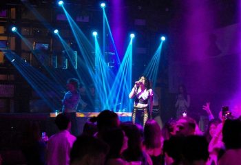 Glamorize Roma: Singer performs at a gay club in Rome, Italy. Blue spotlights illuminate the stage and crowd. Purple lighting adds to the ambiance.