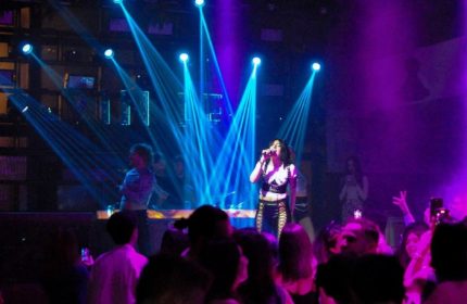 Glamorize Roma: Singer performs at a gay club in Rome, Italy. Blue spotlights illuminate the stage and crowd. Purple lighting adds to the ambiance.