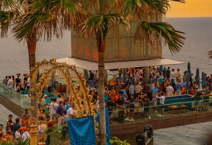 Glitterbox @ Hi Ibiza gay club. Outdoor party scene with palm trees, ocean views, and a lively crowd. Gay travel in Ibiza.
