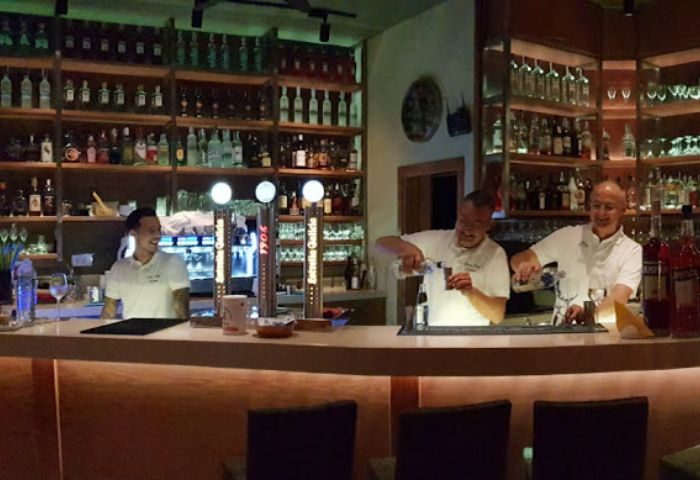 Gran Cafe Latino gay bar in Gran Canaria. Bartenders at work, pouring drinks. Shelves stocked with bottles. Gay travel.