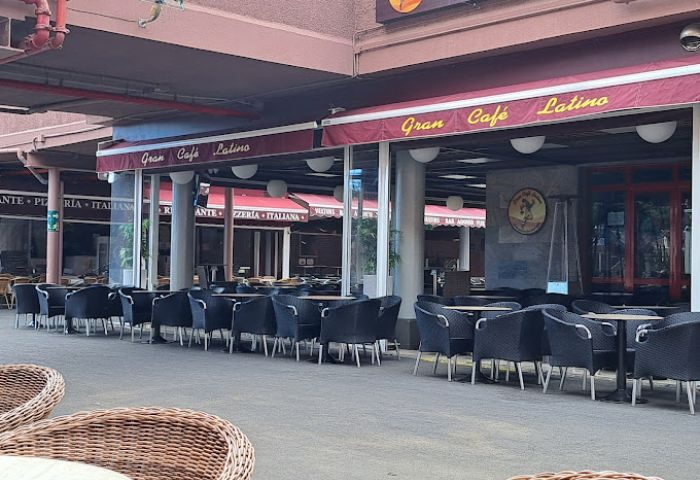 Gran Cafe Latino gay bar in Gran Canaria. Outdoor seating area with tables and chairs under a covered patio. Gay travel advice.