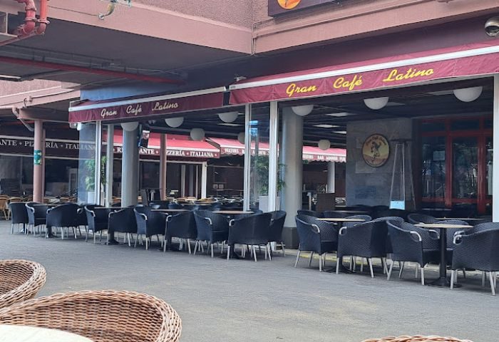 Gran Cafe Latino gay bar in Gran Canaria. Outdoor seating area with tables and chairs under a covered patio. Gay travel advice.