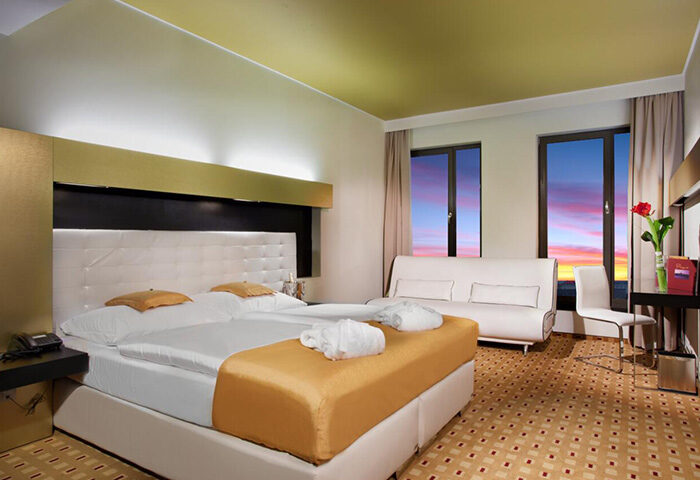 Grandior Hotel Prague room. Modern interior, double bed, sofa, sunset view. Perfect for gay couples visiting Old Town. Gay-friendly hotel.