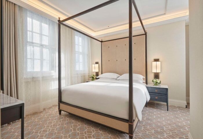 Great Scotland Yard Hotel luxury room. Four-poster bed, white linens, bedside tables. Most booked hotels in London Central. Gay travel.
