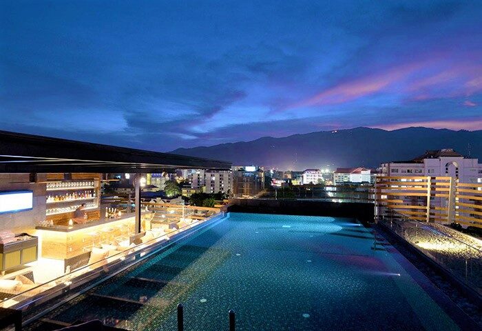 Akyra Manor Chiang Mai rooftop pool and bar at night. Great value luxury gay hotel on Nimman Rd, Thailand. Cityscape view.