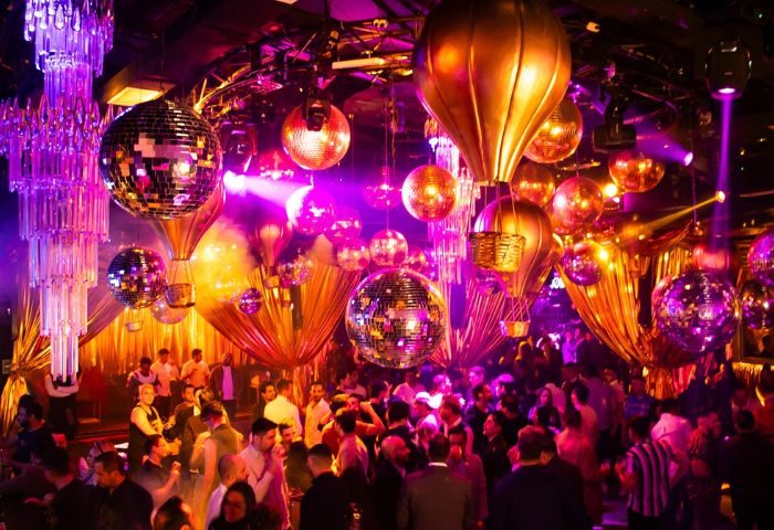 Guilt Night Club, a gay bar in Mexico. Disco balls and hot air balloon decorations hang above a crowded dance floor. Purple lighting.