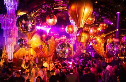 Guilt Night Club, a gay bar in Mexico. Disco balls and hot air balloon decorations hang above a crowded dance floor. Purple lighting.