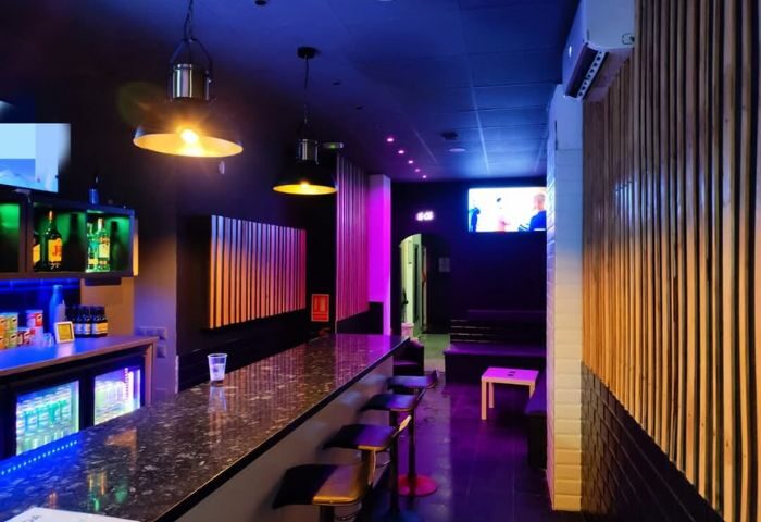 Interior of H2O Sauna, a gay sauna in Benidorm, Spain. Bar area with stools, drinks, and lounge seating. Nightlife scene.