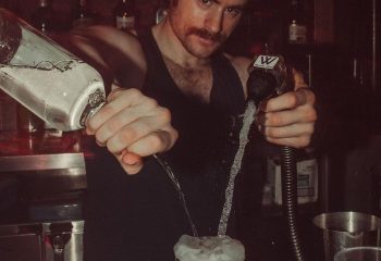 Bartender at HUSH HK, a gay bar and dance club in New York, pouring drinks. Nightlife scene for gay men traveling to NYC.