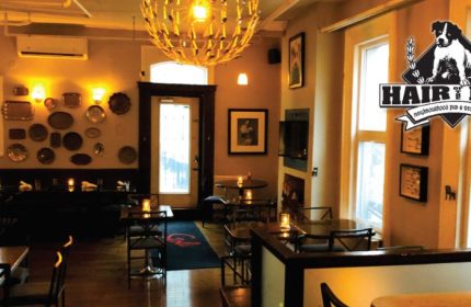Interior view of Hair of the Dog Pub in Toronto. Warm lighting, tables, and decor create a cozy atmosphere. Gay travel recommendation.