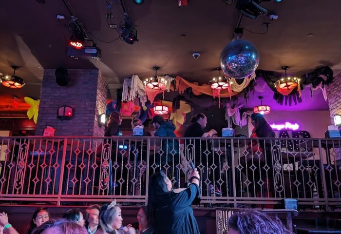 Hamburger Mary's Long Beach experience. Crowded gay bar with disco ball, stage, and patrons enjoying a night out. Fun, lively atmosphere.