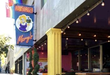 Hamburger Mary's WeHo location exterior. Iconic neon sign with a cartoon woman holding a burger. Rainbow flag. Gay travel WeHo.