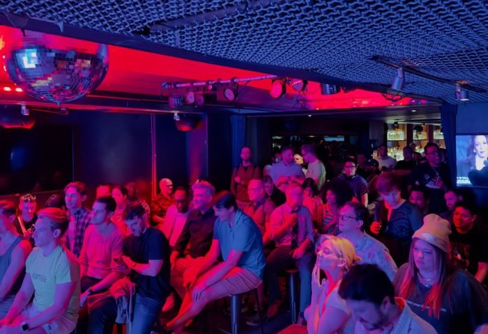 Hardware Bar in New York: A crowded gay bar scene with red and blue lighting, a disco ball, and people seated and standing. Nightlife.