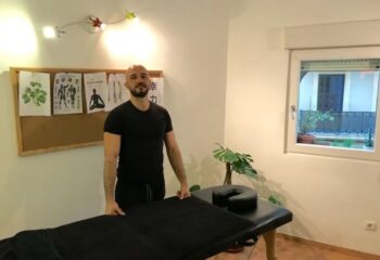 Gay massage in Barcelona: Man stands by massage table at Healing Hands BCN. Relaxing spa for gay men's travel.