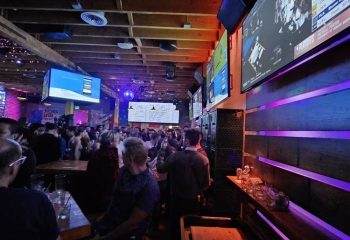 Hi Tops dancefloor: Gay bar interior with a crowd, TVs showing sports, and a lively atmosphere. Gay travel destination.