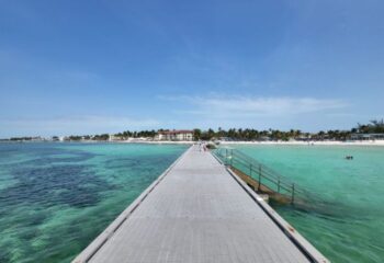 Higgs Beach pier in Key West, a gay-friendly travel destination. Turquoise water, palm trees, and white sand. Ideal for gay cruises.