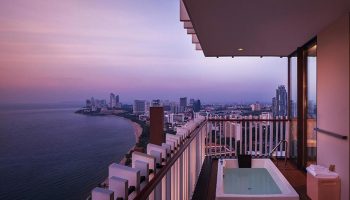 Hilton Pattaya luxury beachfront hotel view at dusk. Popular gay hotel in Pattaya with balcony jacuzzi overlooking the city and ocean.