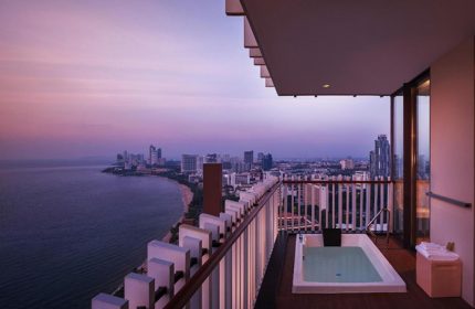 Hilton Pattaya luxury beachfront hotel view at dusk. Popular gay hotel in Pattaya with balcony jacuzzi overlooking the city and ocean.