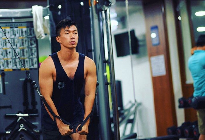 Gay man at Holiday Inn Resort Phuket gym. Stay fit while traveling in Phuket. Hotel fitness center with cable machine.