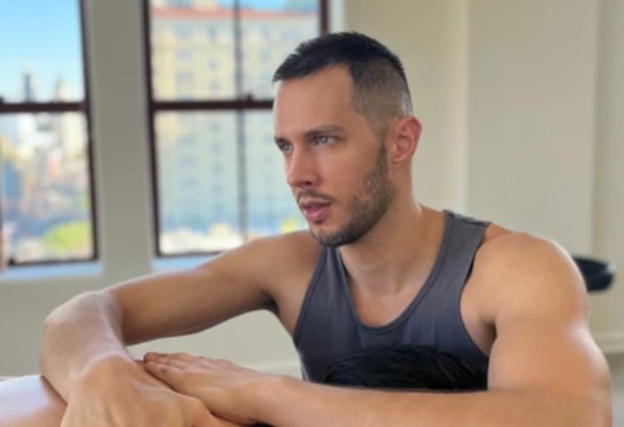 Jeremie, Hollywood massage therapist, offers gay men travel advice. Handsome man in tank top with city view. Gay travel massage in Hollywood.