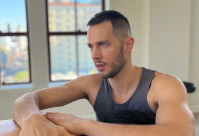 Jeremie, Hollywood massage therapist, offers gay men travel advice. Handsome man in tank top with city view. Gay travel massage in Hollywood.