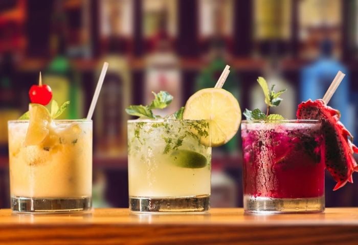 Three colorful cocktails on a bar in a New York gay lounge. Refreshing drinks for men to enjoy while traveling in NYC.