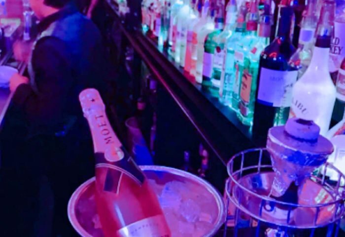 Hombres Lounge in New York: Bar scene with Moët champagne in ice bucket. Gay travel nightlife, drinks, and lounge atmosphere.
