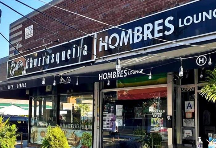 Hombres Lounge in New York. Exterior of the gay-friendly restaurant, Churrasqueira Hombres Lounge, with string lights and rainbow flag.
