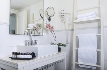 Shalom Hotel Relax bathroom. Gay hotel Tel Aviv honeymoon inspiration. White sink, ladder with towels, orchid, hair dryer. Atlas Boutique Hotel.