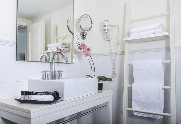 Shalom Hotel Relax bathroom. Gay hotel Tel Aviv honeymoon inspiration. White sink, ladder with towels, orchid, hair dryer. Atlas Boutique Hotel.