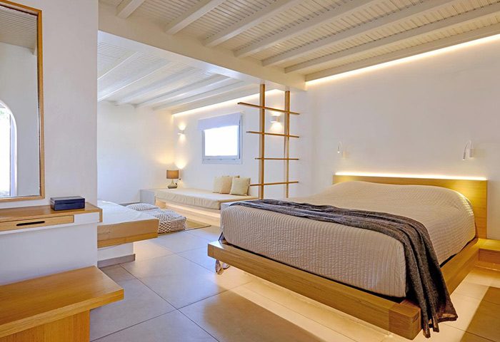 Andronikos Hotel, Mykonos: Honeymoon suite idea for gay couples. Minimalist white room with bed, daybed, and wood accents. Luxury gay travel.