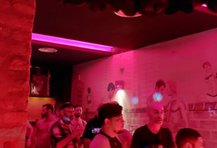 Inside Hot Dog Club Milan, a gay sauna. Men gather under pink lights, with suggestive art on the walls. Gay travel advice.