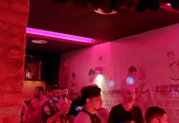 Inside Hot Dog Club Milan, a gay sauna. Men gather under pink lights, with suggestive art on the walls. Gay travel advice.