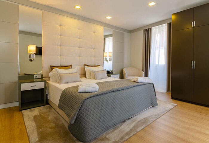 Hotel Borges Chiado bedroom. Best gay hotel in Lisbon near Trombeta Bath gay sauna. Room with bed, wardrobe, and bedside table.