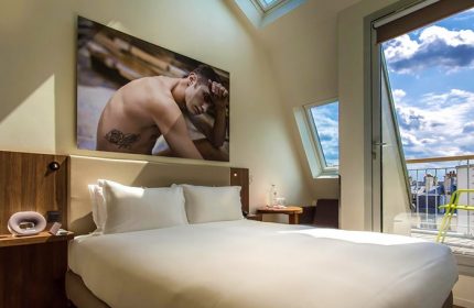 Hôtel Jules & Jim Adults-Only Gay Hotel room in Paris. Balcony view, skylight, and art featuring a shirtless man. Gay travel advice.
