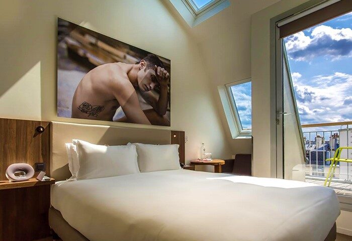 Hôtel Jules & Jim Adults-Only Gay Hotel room in Paris. Balcony view, skylight, and art featuring a shirtless man. Gay travel advice.