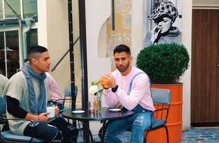 Gay couple at Hôtel Jules & Jim, Paris. Stylish men sit at a table in this famous gay hotel, perfect for honeymoon couples. Paris gay travel.