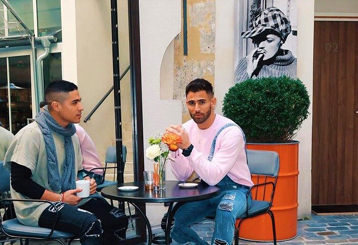 Gay couple at Hôtel Jules & Jim, Paris. Stylish men sit at a table in this famous gay hotel, perfect for honeymoon couples. Paris gay travel.