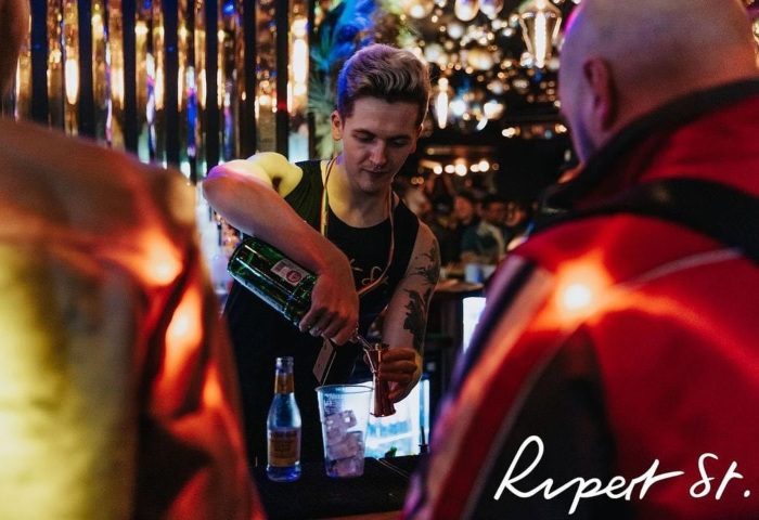 Bartender pours a drink at Rupert Street Bar, London's hottest gay bar. See the crowd at this popular gay travel destination.